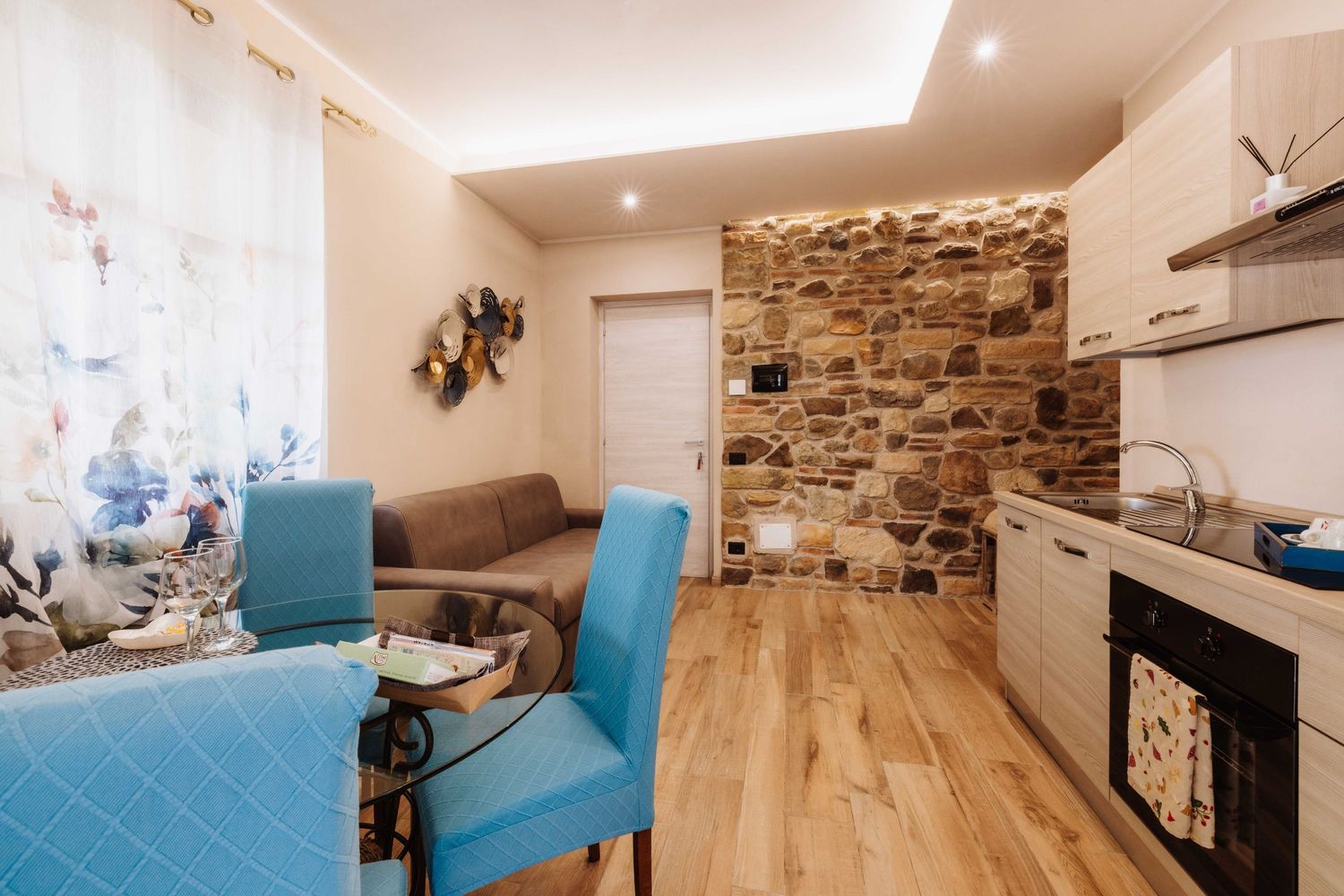 Modern living room with hardwood floors, stone accent wall, and turquoise furniture accents.