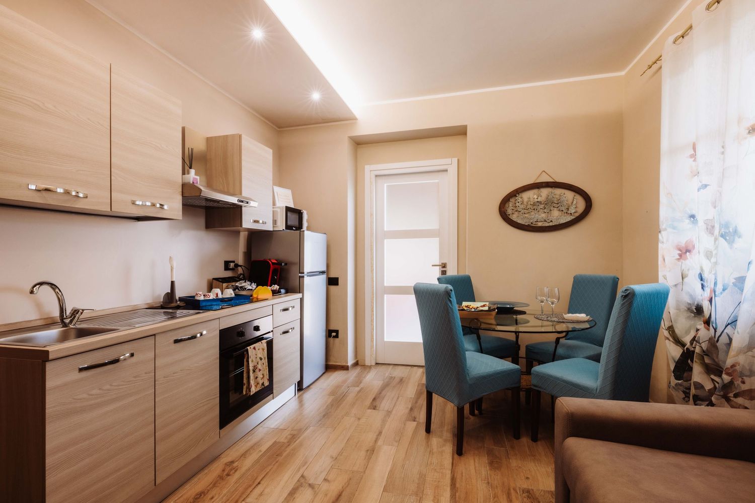 Modern apartment interior with wooden floors and white walls showcases an open concept living and kitchen space.