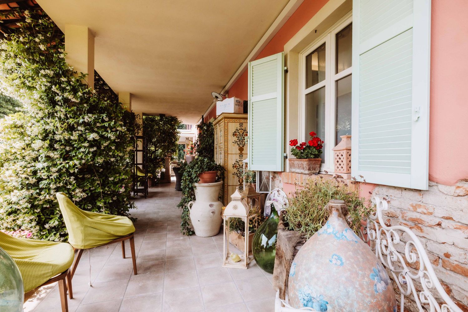 A long covered porch with white columns and hanging flower baskets extends along a pink-painted building.