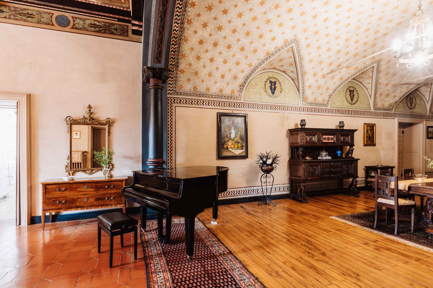 Panoramic view of a historic interior room with hardwood floors, ornate wallpaper, and antique furniture and pianos.