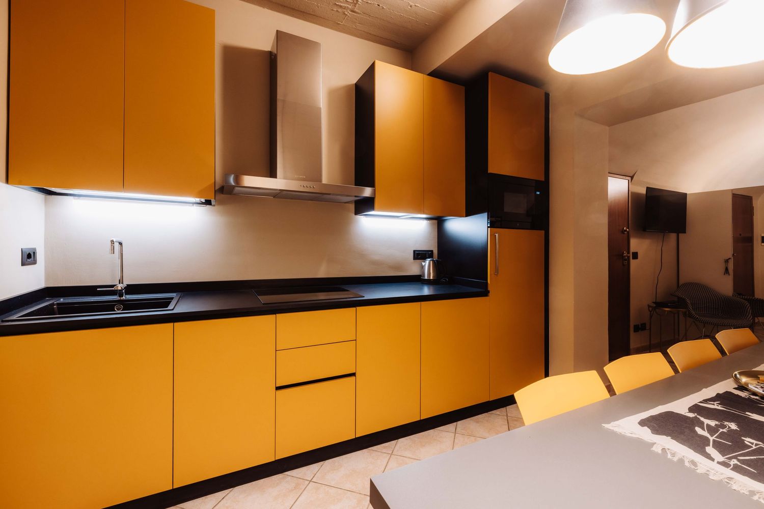 Modern kitchen with sleek orange cabinets and black accents features minimalist design and recessed lighting.