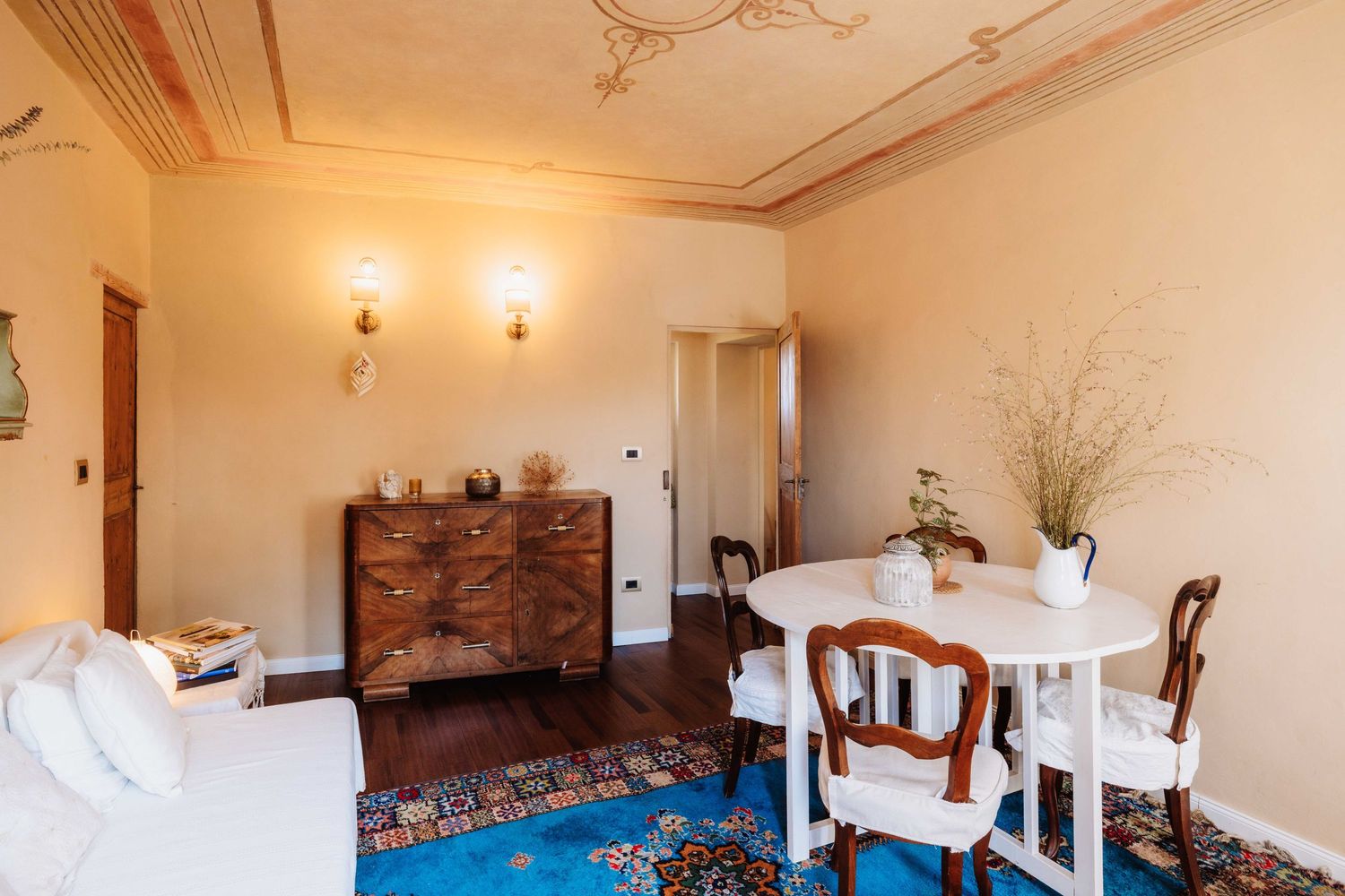 Bright interior room with white walls and wooden beams featuring elegant dining furniture.