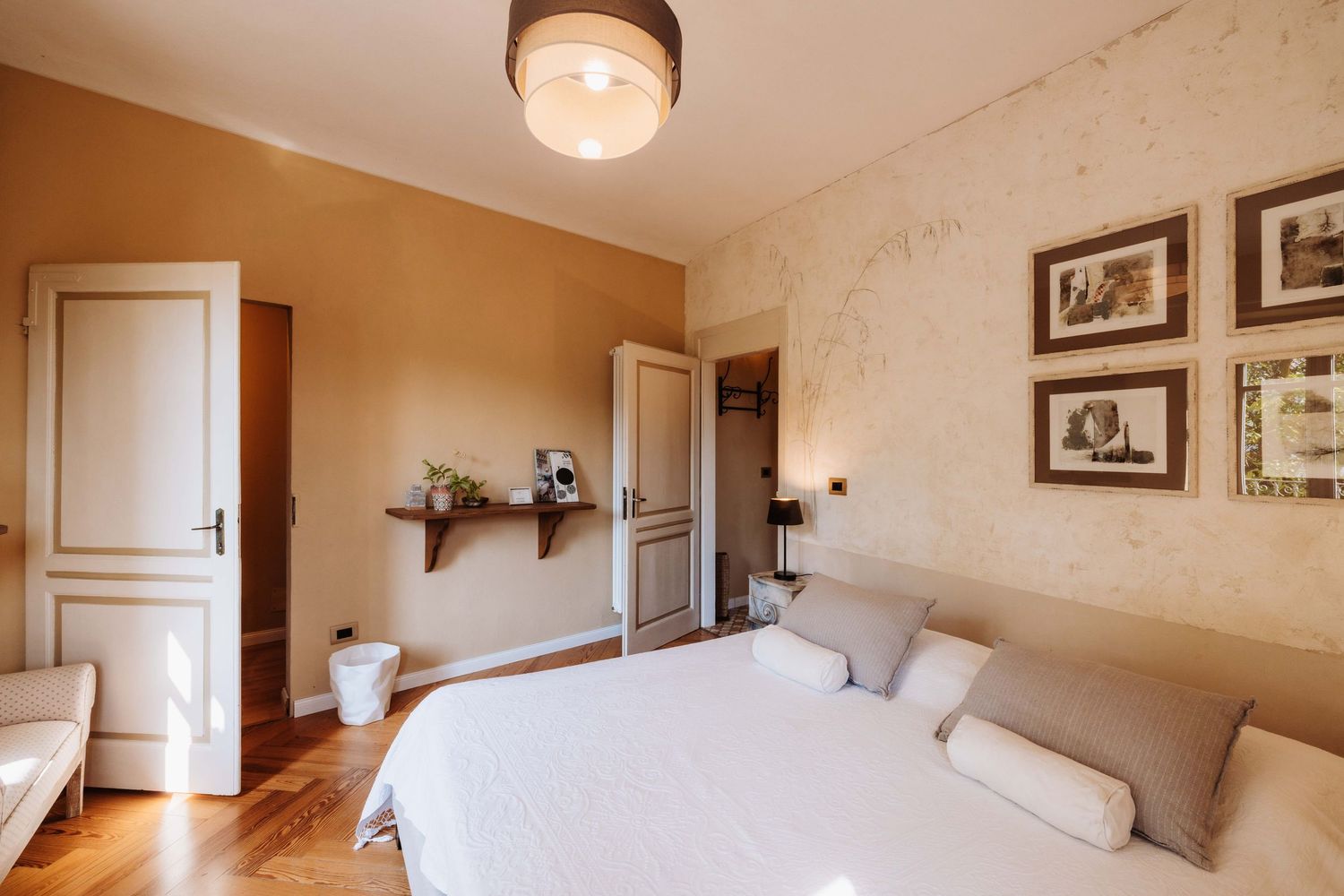 Warm beige bedroom interior with white bedding and natural lighting from windows.
