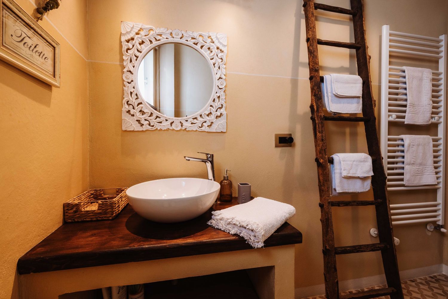 A modern bathroom interior with warm beige walls, a freestanding tub, and decorative ladder towel rack.