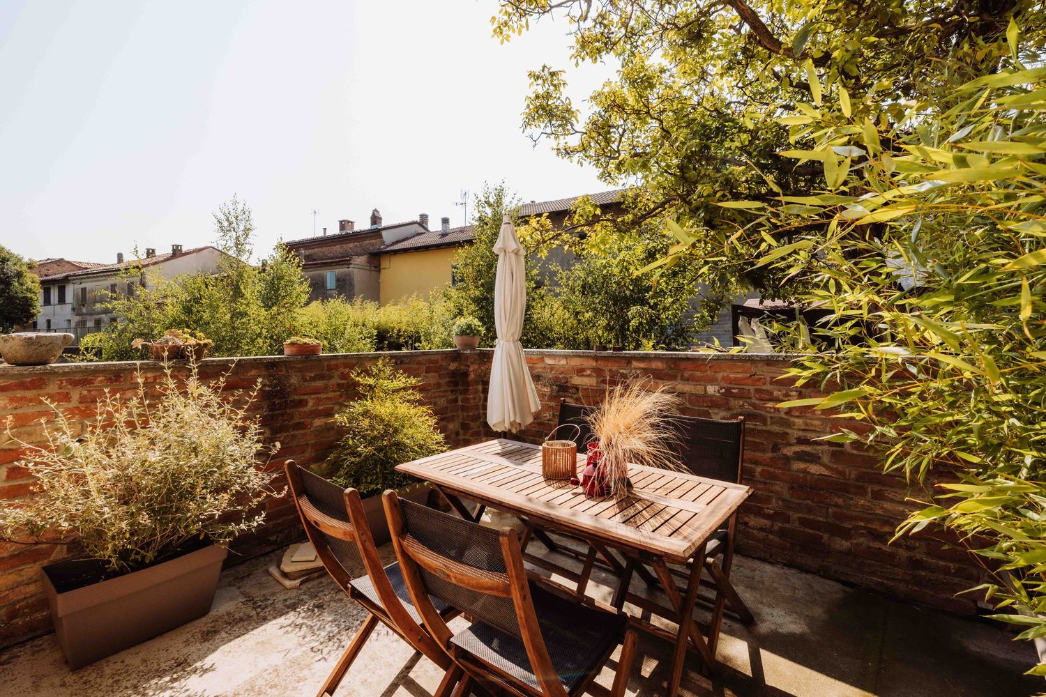 Wooden lounge chairs and planters create a cozy rooftop garden terrace with lush greenery and city views.