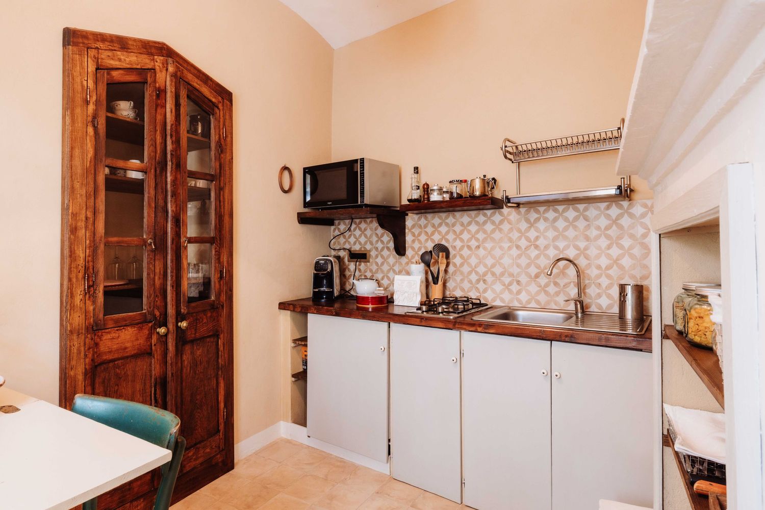 A panoramic view of a modern kitchen interior with white cabinets, wooden doors, and stainless steel appliances.