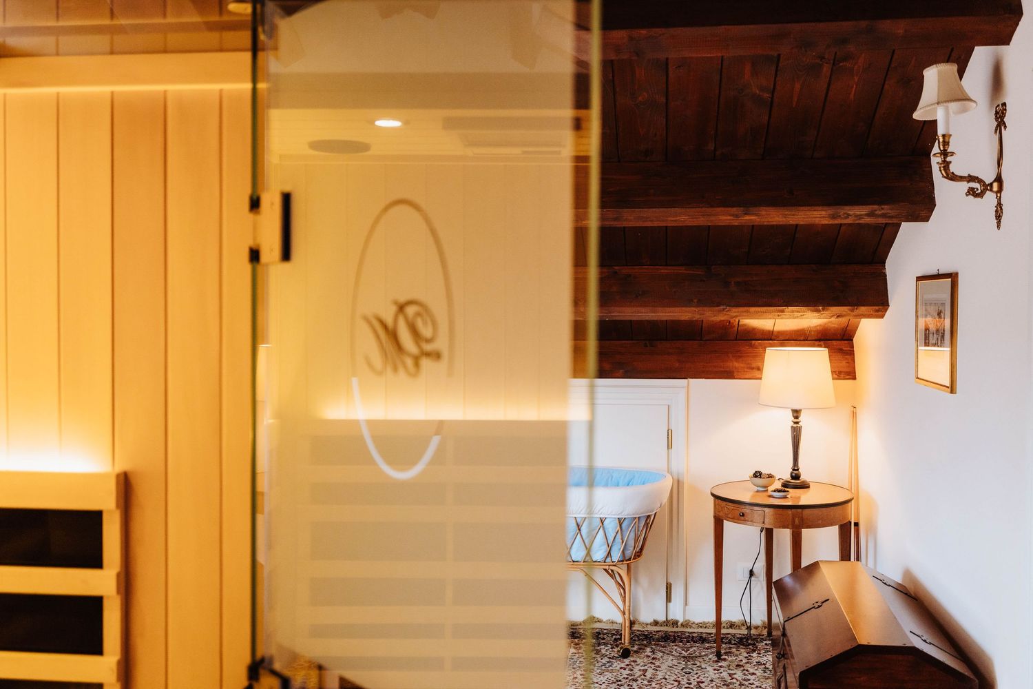 Cozy interior corner with wooden beams, white walls, and warm lighting featuring a rustic door and side table.