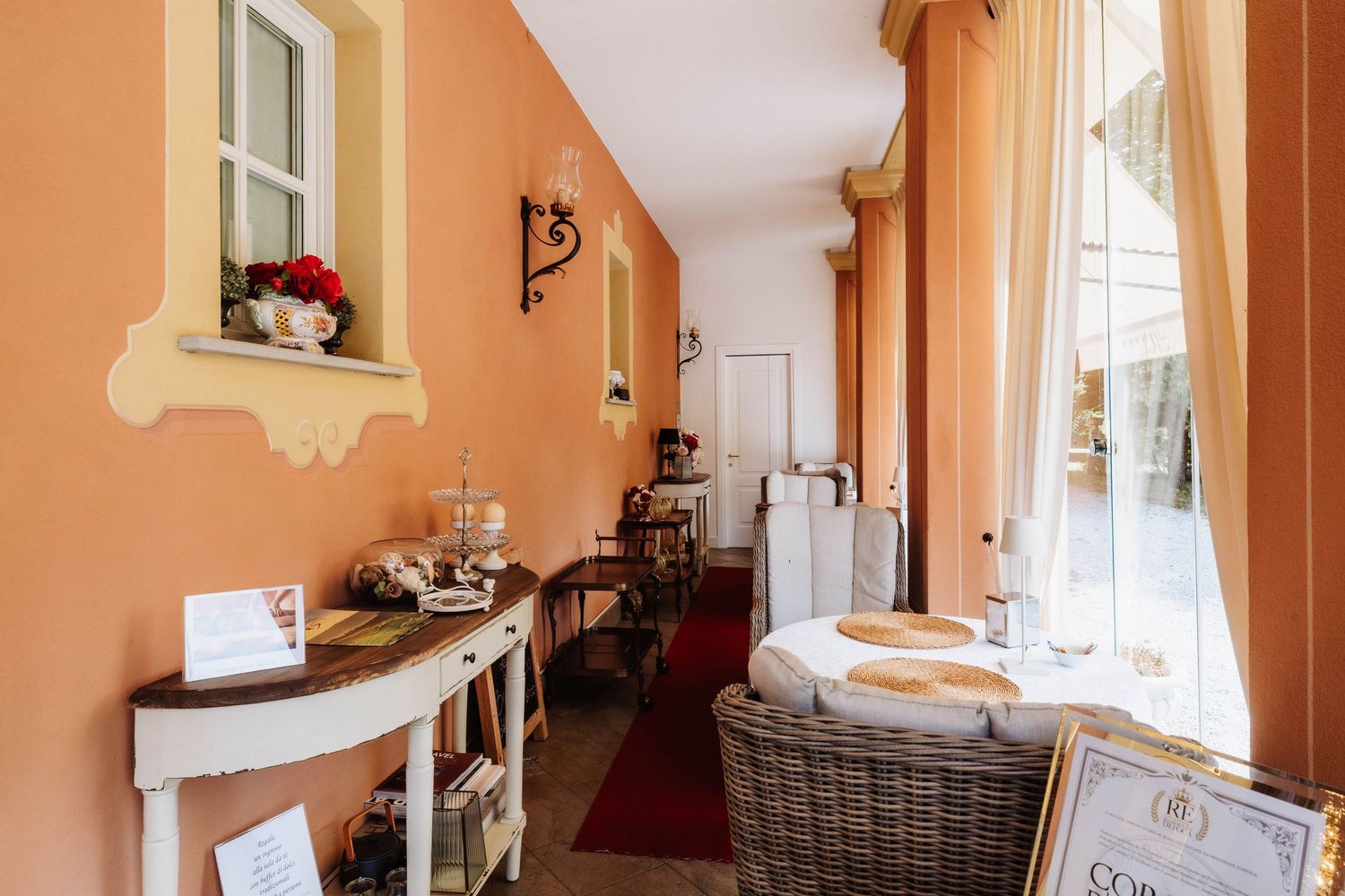 Peach-colored hallway with white trim and decorative wall mirror leads to a bright, sunlit room.