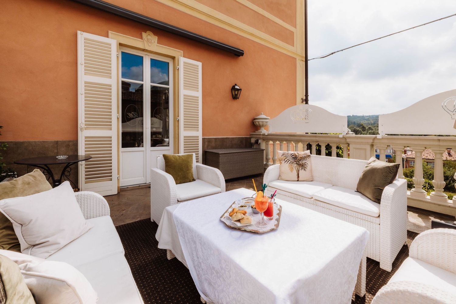 Elegant terrace with white outdoor furniture and breakfast tray overlooking Mediterranean style balustrade.