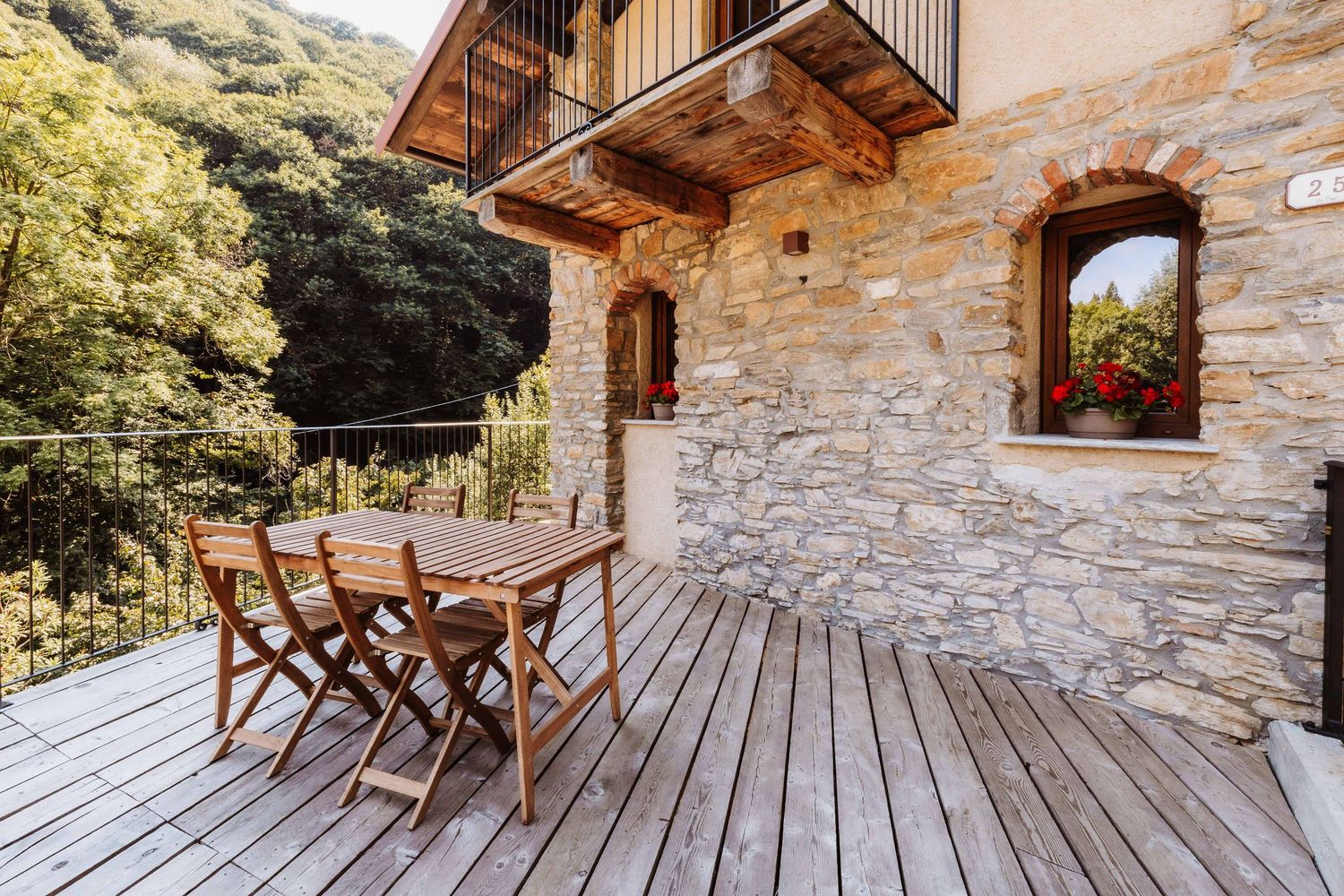 Rustic wooden deck chairs arranged on a stone cabin patio with mountain views in the background.