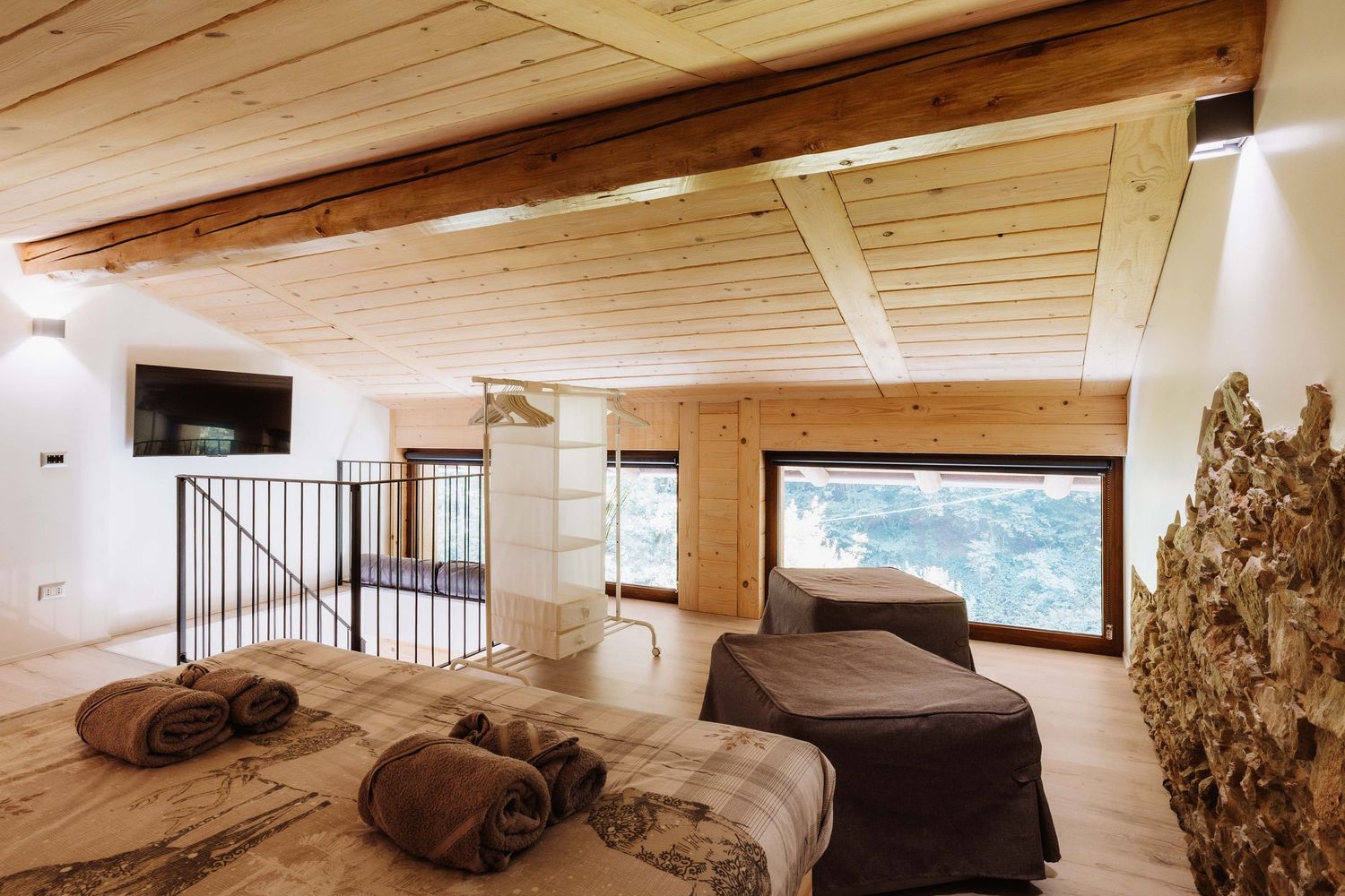 Modern loft-style bedroom with wooden ceiling beams, white walls, and minimalist furnishings creates a cozy atmosphere.