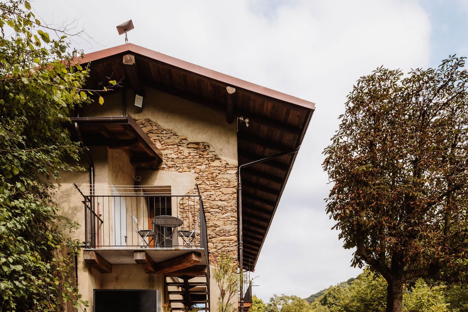 Row of rustic stone and wood chalets nestled among trees in a mountain village setting.