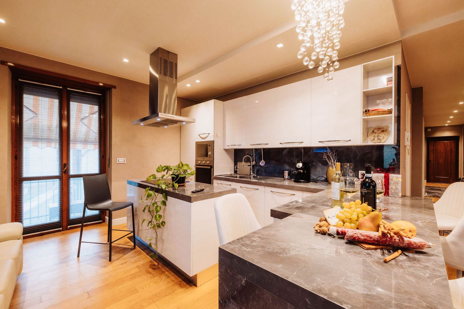 Modern open concept kitchen with white countertops, pendant lights, and wood cabinetry in a luxury home.