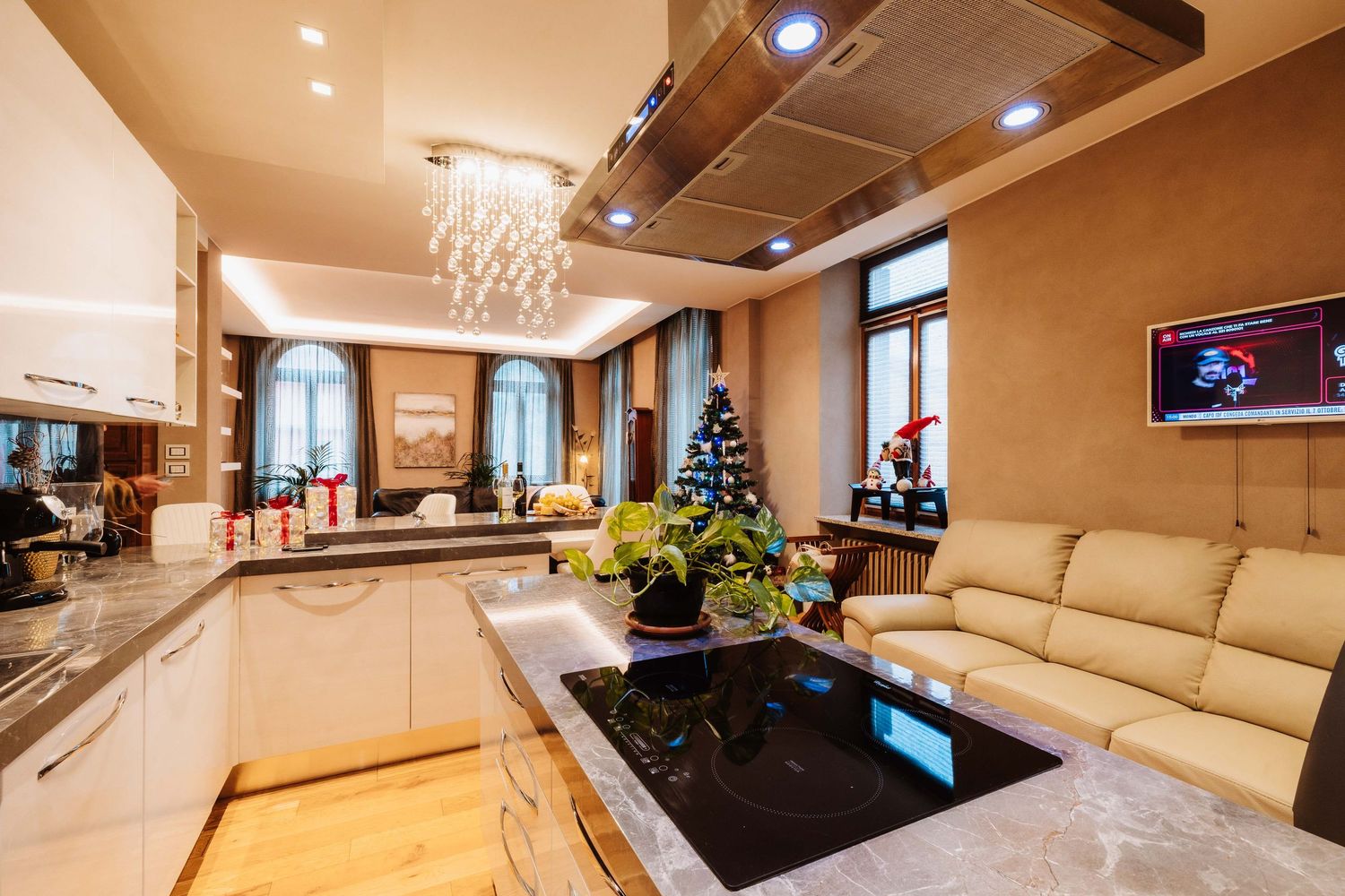 Modern luxury apartment interior with beige leather sectional sofa and crystal chandelier in an open concept living space.