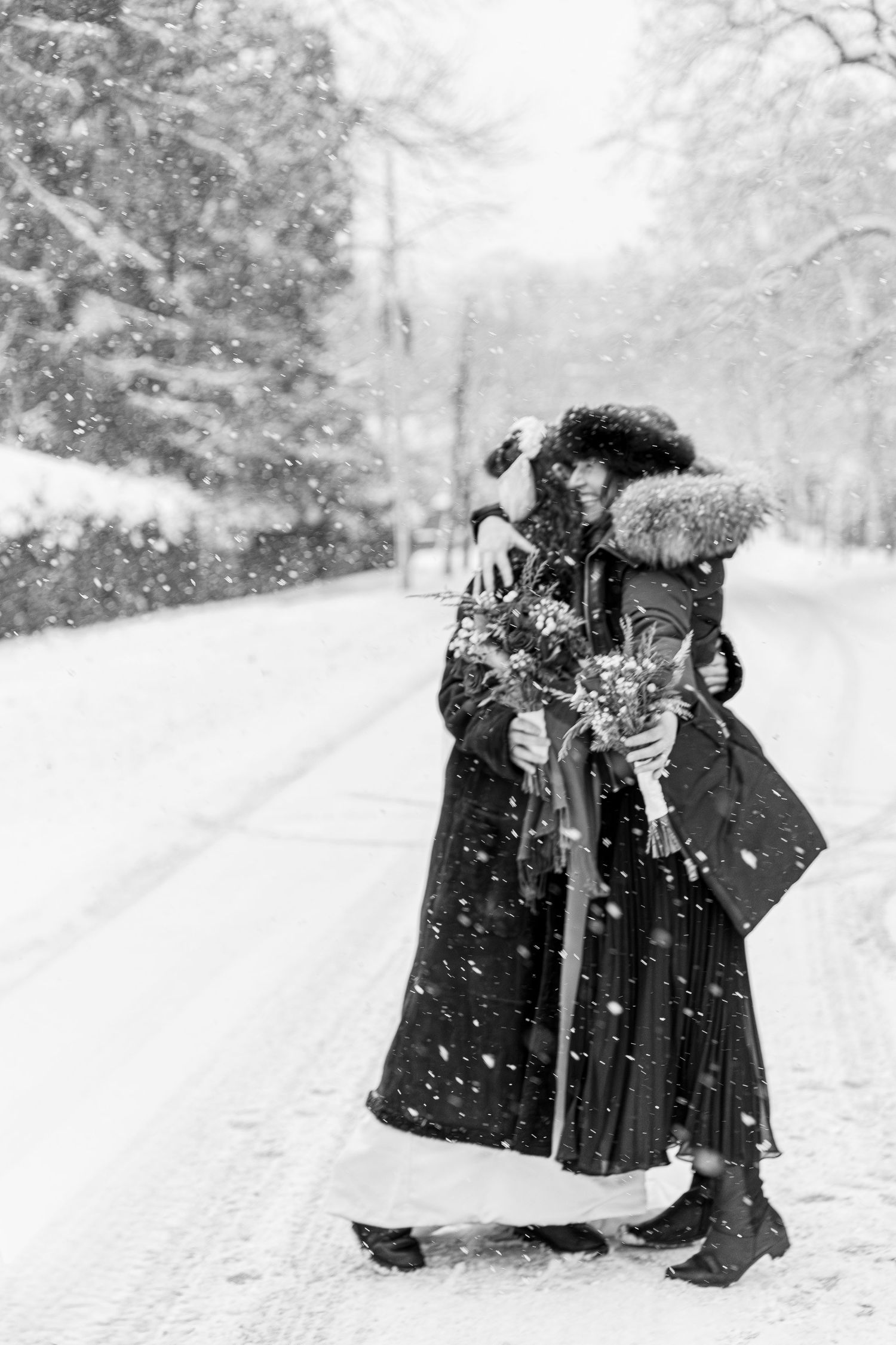 Bride and groom embracing and kissing on a snowy road during winter wedding celebration.