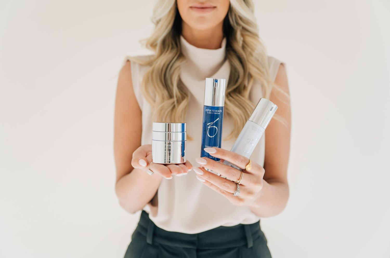 Beauty product bottles displayed against a white background with hands holding skincare items.