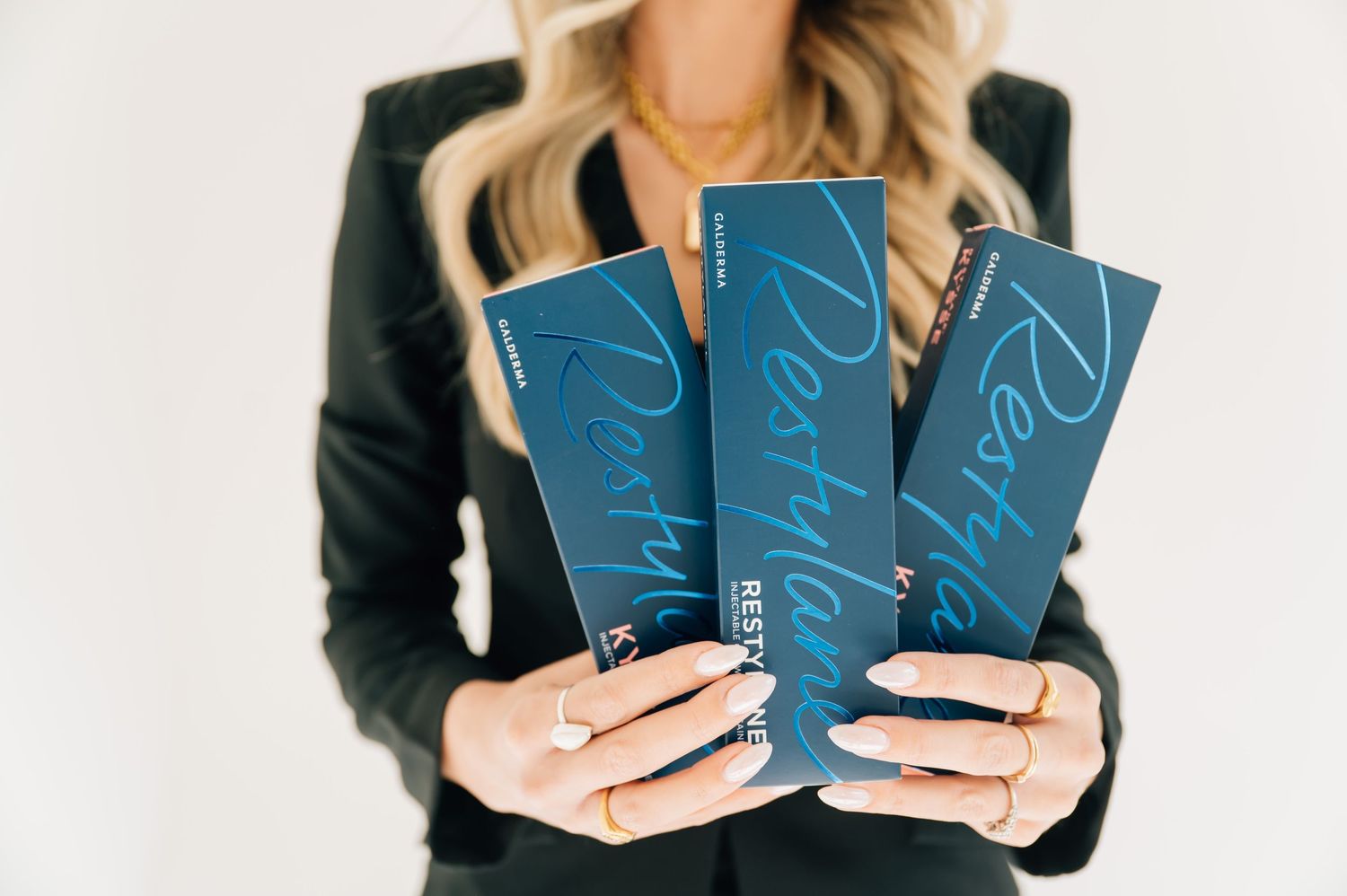 A person in a black blazer holds blue notebooks while displaying various angles of the stationery products.
