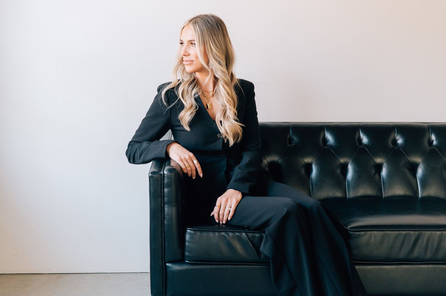 Professional lifestyle photoshoot series showing a person in black attire posing on a dark leather couch.