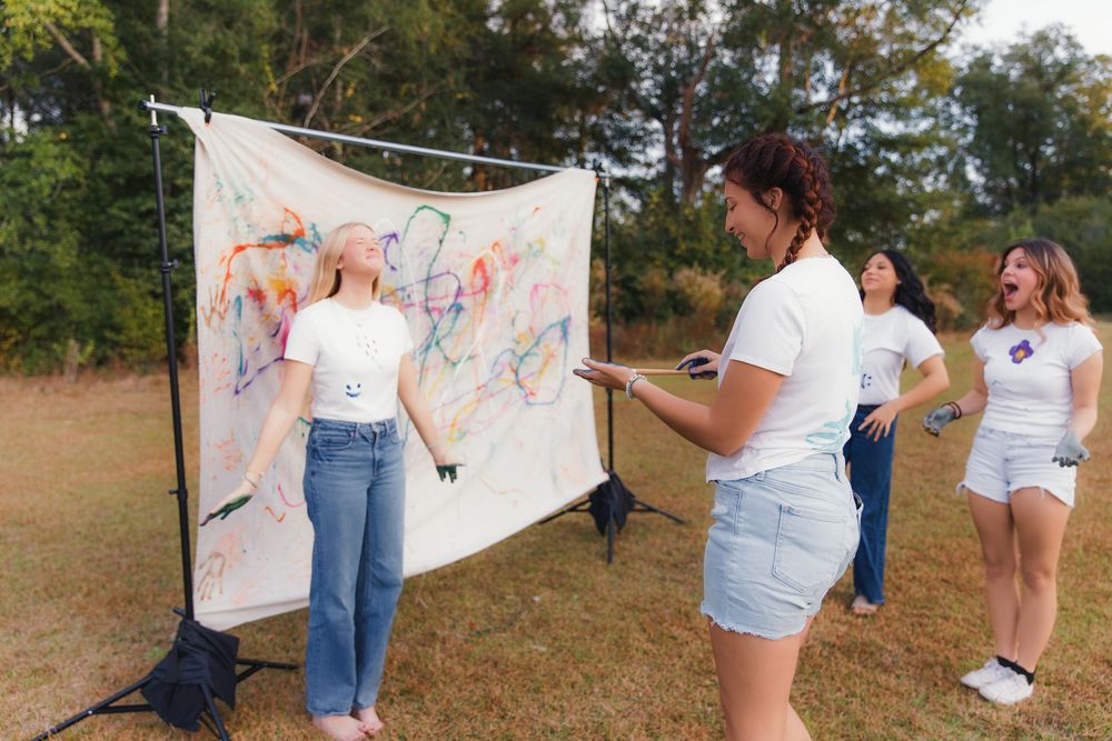 A group of people holding a large white banner with colorful drawings in an outdoor setting.