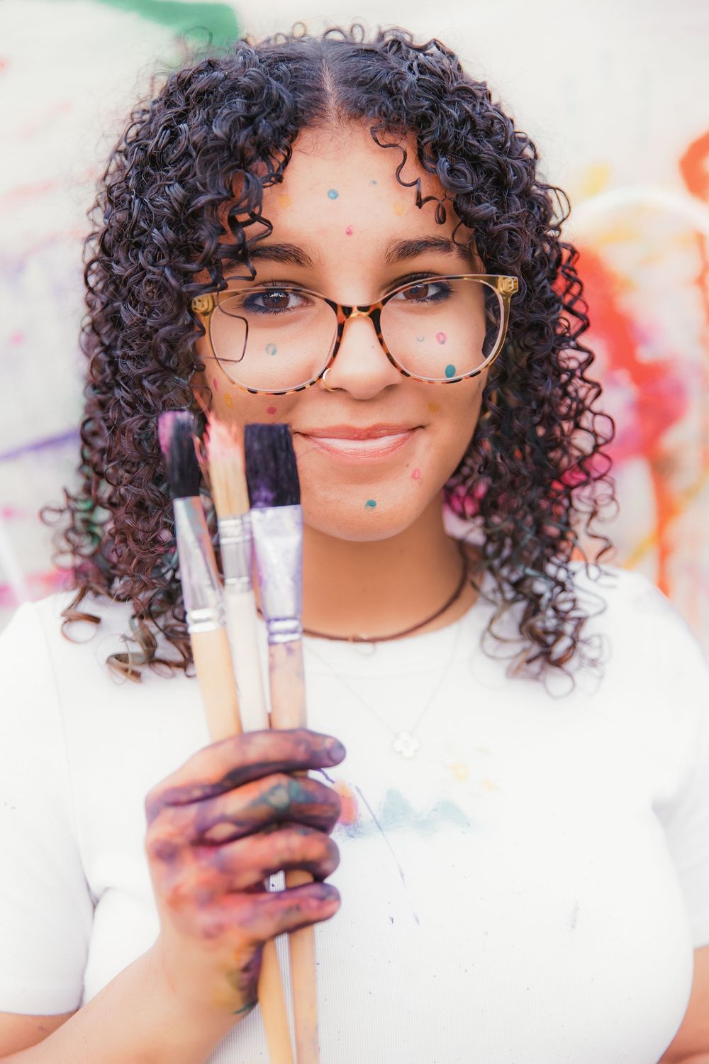 Artistic beauty shot with makeup brushes and colorful confetti details against white background.