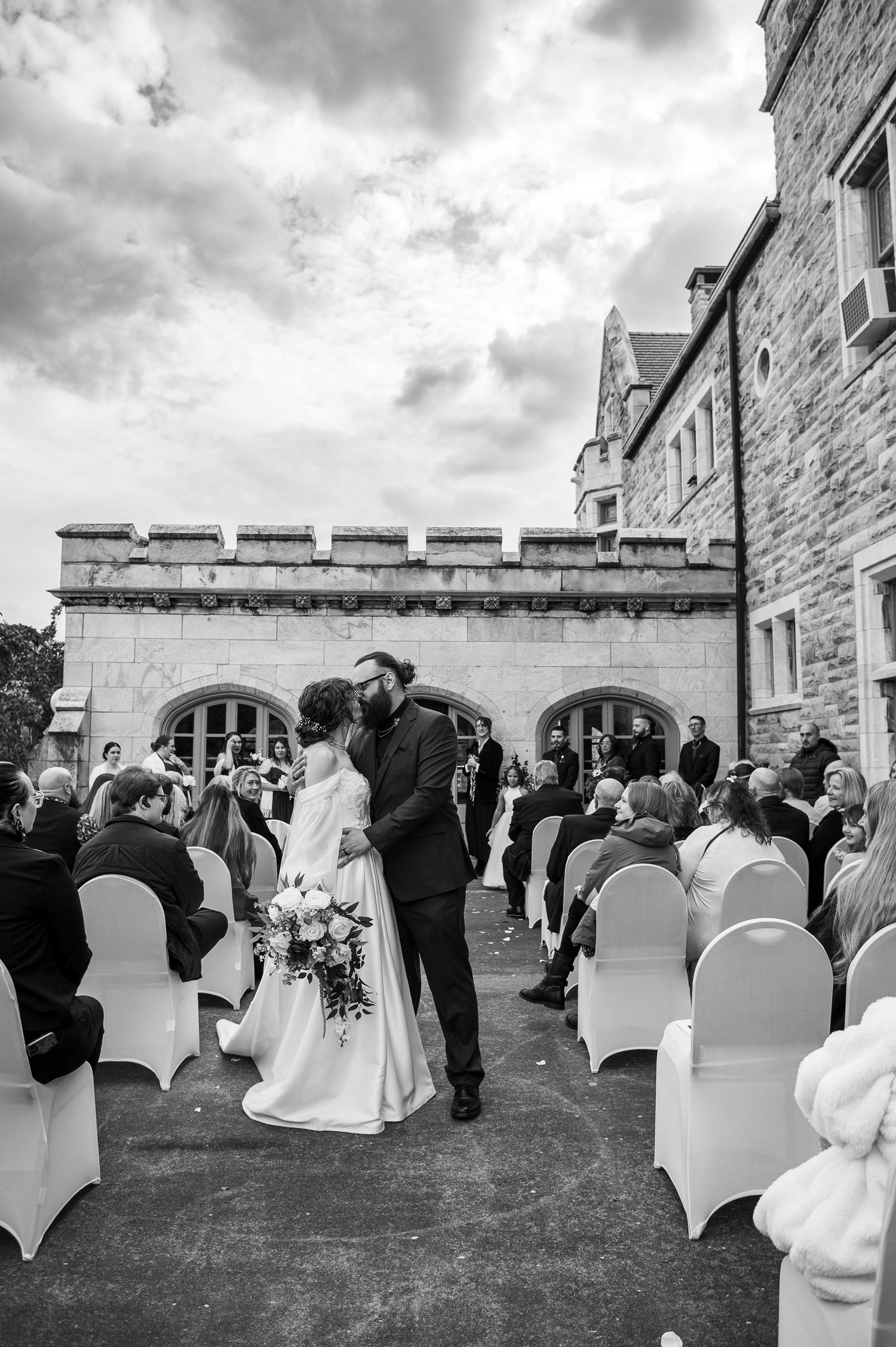 A scenic wedding photo series showing a historic stone castle venue with towers and turrets against a cloudy sky.
