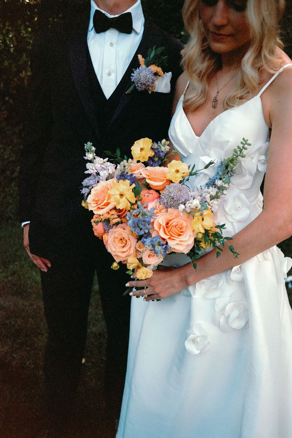 Close-up shots of wedding couple holding peach and blue floral bouquets.