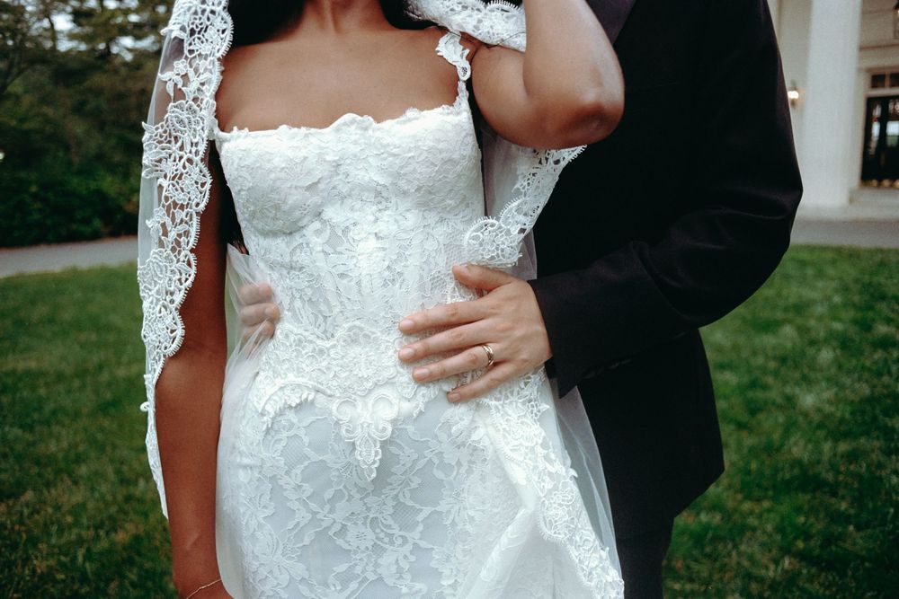 Close-up details of an elegant white lace wedding dress with delicate embroidery patterns.
