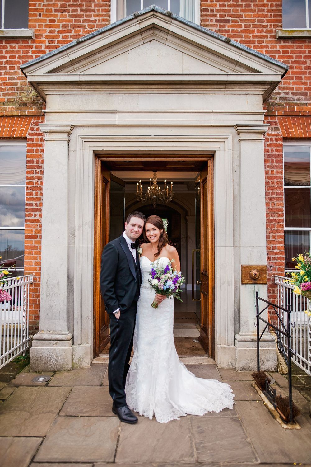 Wedding couple poses in sequence of romantic moments in front of a historic brick building's elegant doorway.