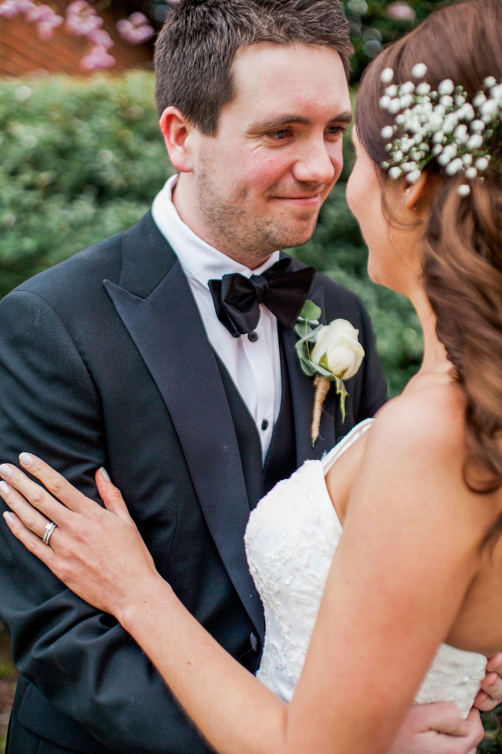 A tender moment between newlyweds showing the groom in a black tuxedo and bride in white lace during their wedding ceremony.