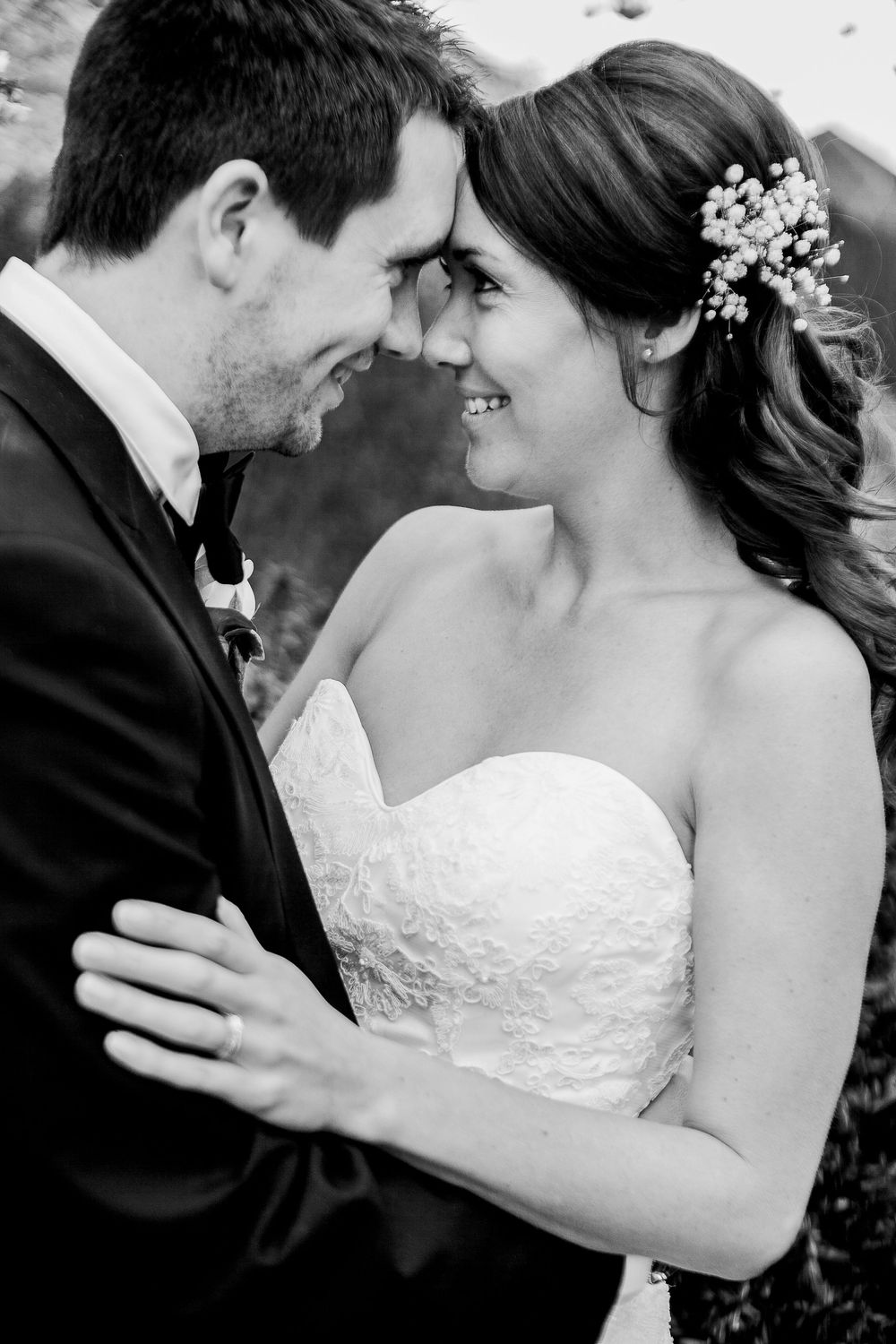 Black and white wedding portrait of newlyweds sharing an intimate moment with foreheads touching.