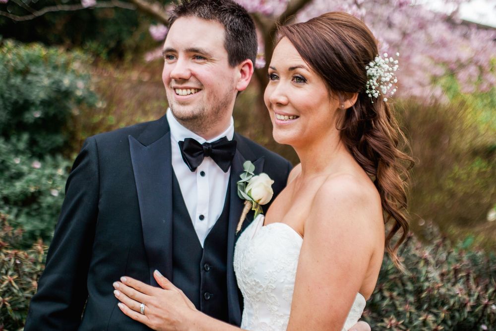 A bride and groom share a joyful moment together outdoors surrounded by beautiful fall foliage.