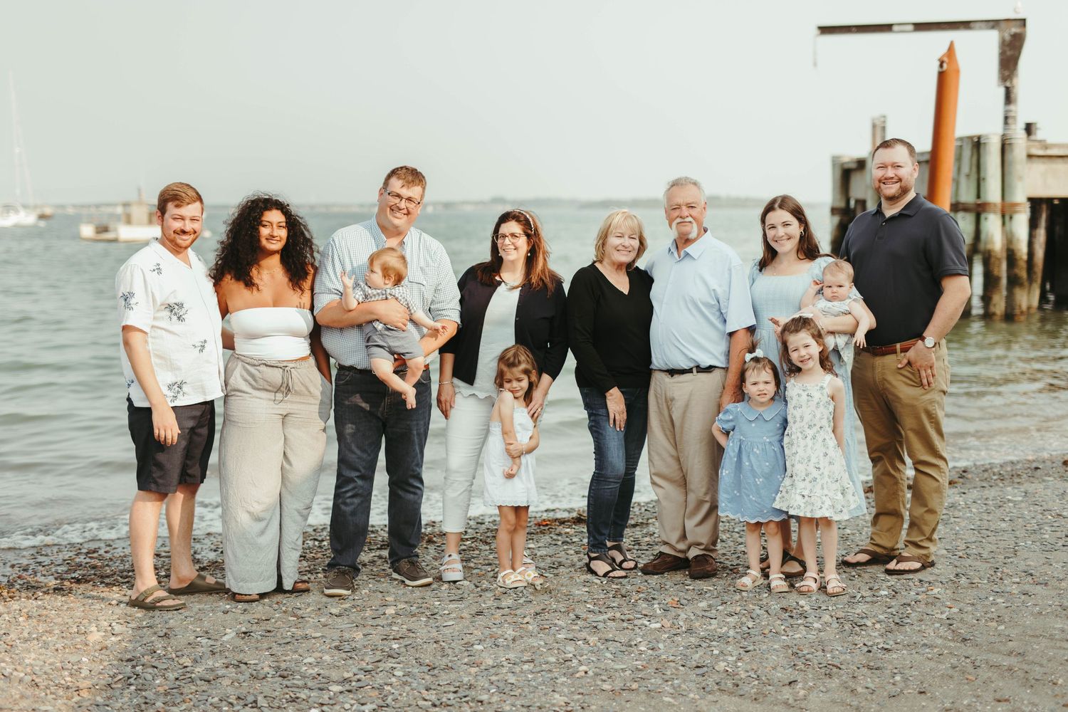 Extended family gathers for casual group portraits on sandy beach at sunset.