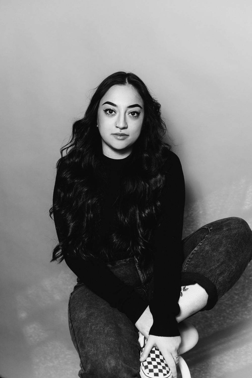 A black and white portrait series showing someone with dark hair sitting against a light background in various poses.
