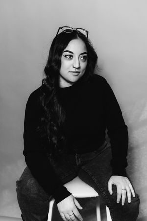 Black and white portrait series showing someone in dark clothing against a light background posing in different positions.