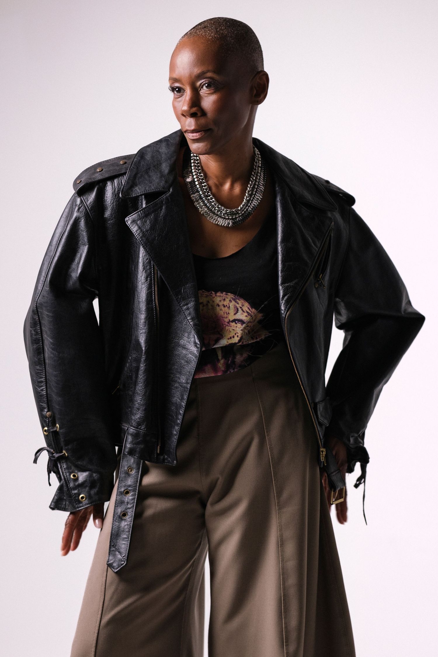 Editorial fashion poses in black leather jacket and brown wide-leg trousers.