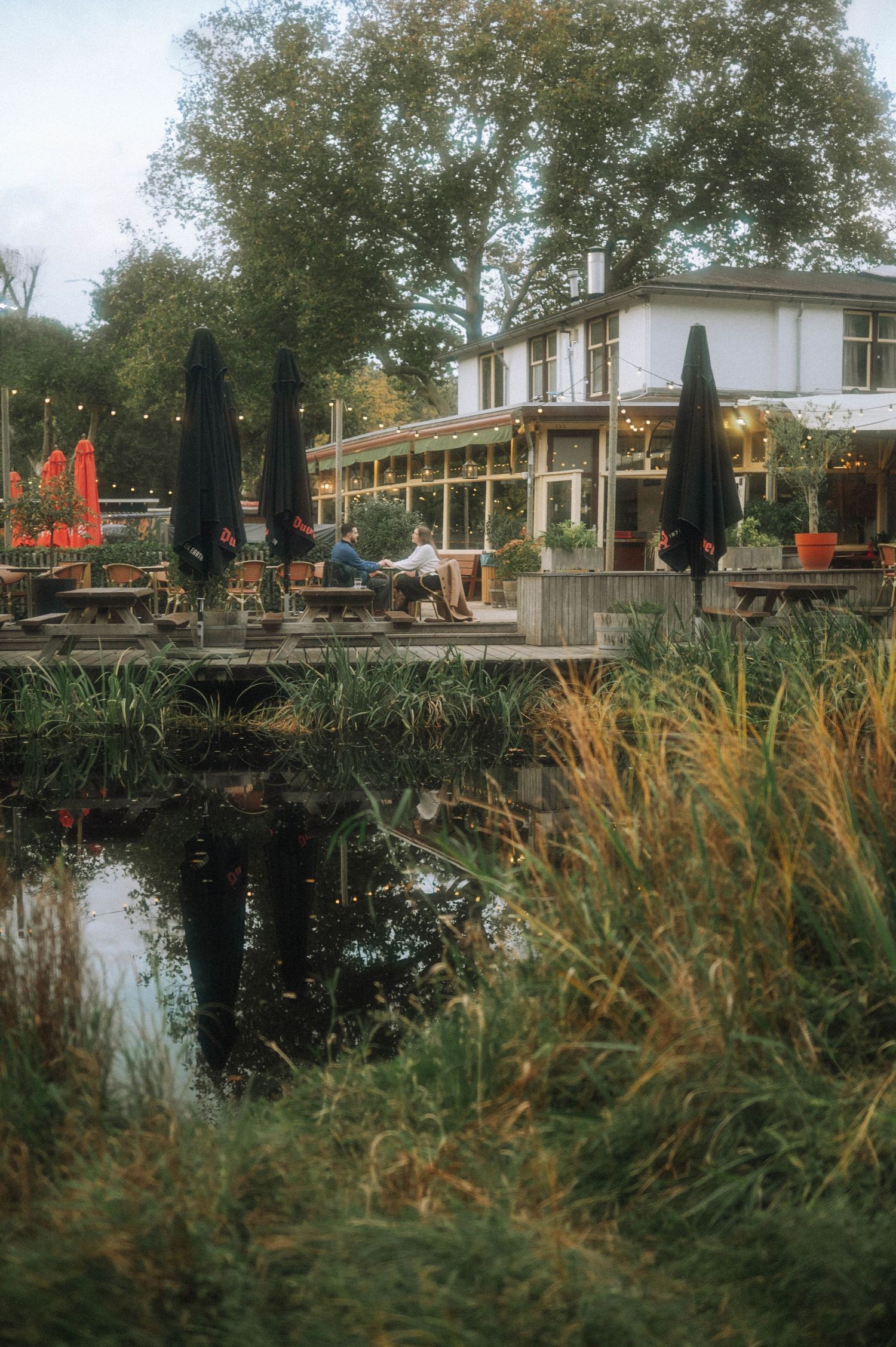Waterfront restaurant in Vondelpark. Couple drinking coffee after secret proposal moment.