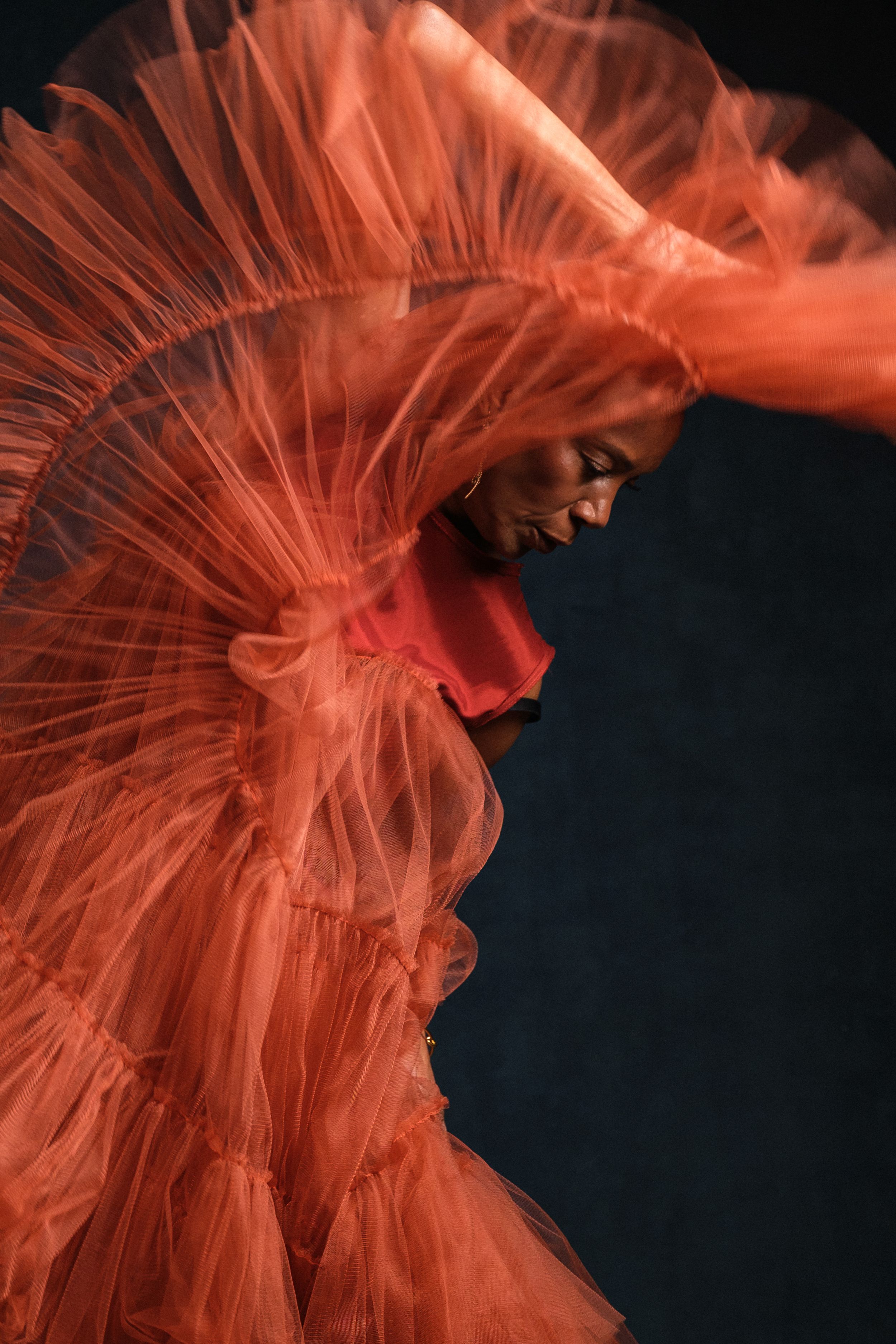 Ethereal movement captured in flowing red fabric against dramatic black background.