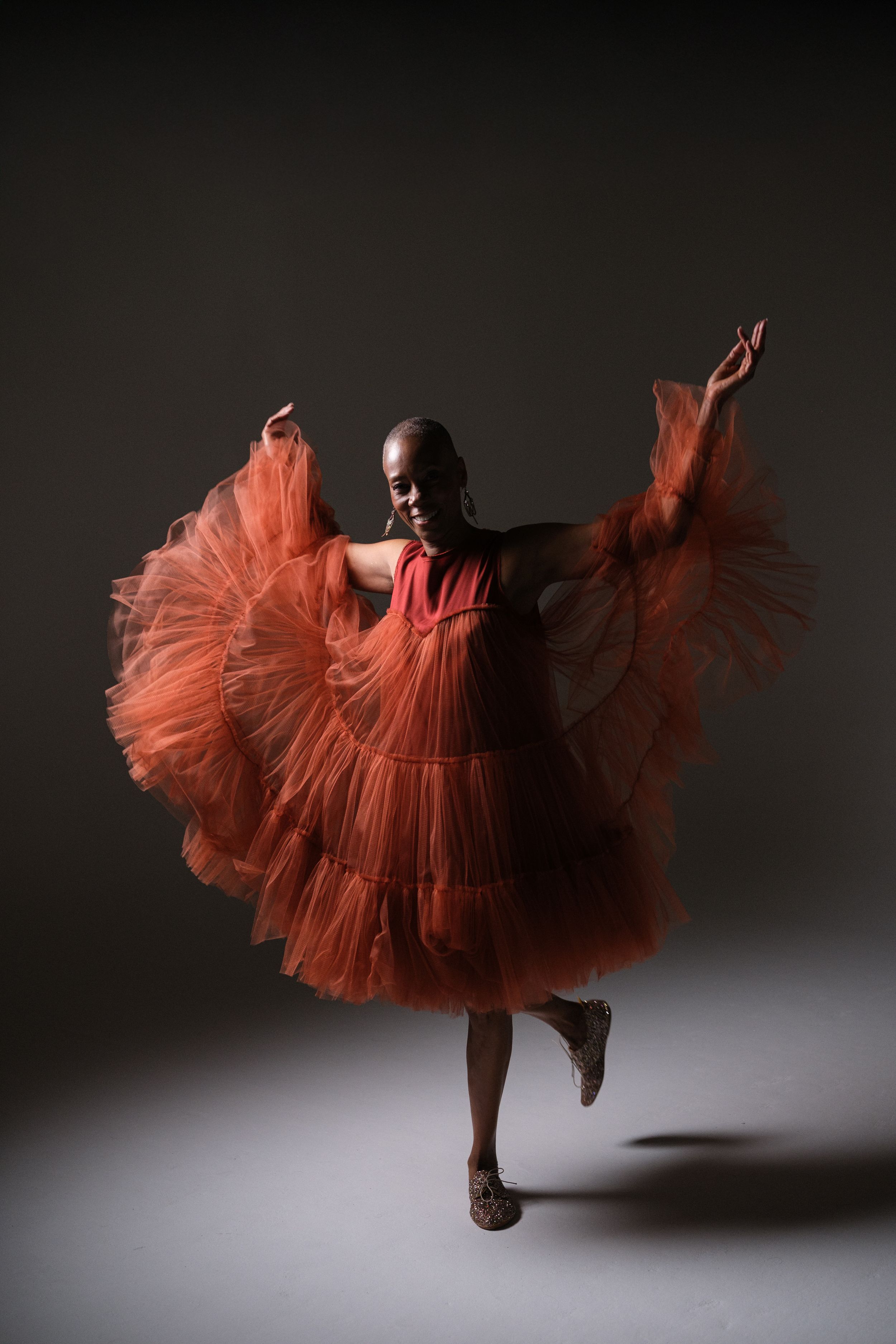 Dynamic dance movement in flowing red tulle dress creates dramatic silhouette.