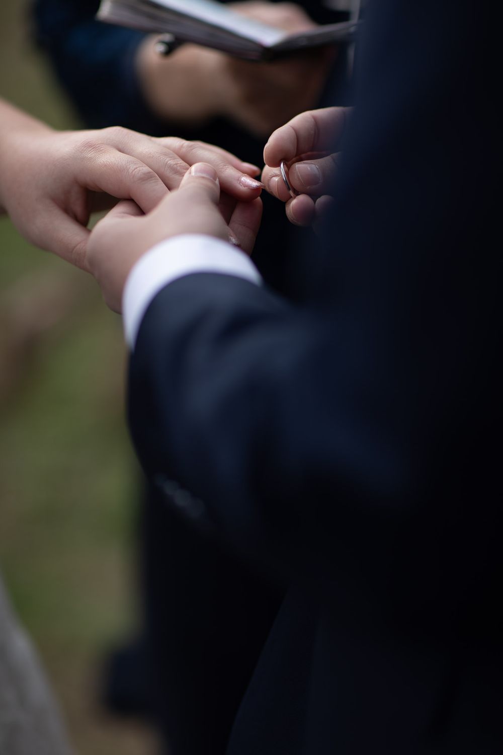 Groom putting wedding ring on bride's finger during wedding ceremony