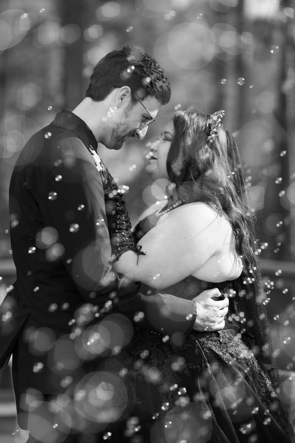 Bride and groom in black and white behind bubbles
