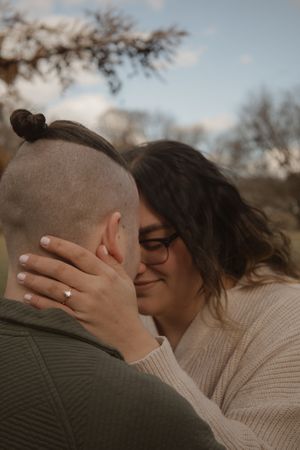 A romantic couple sharing a tender kiss outdoors during golden hour while wearing cozy sweaters.