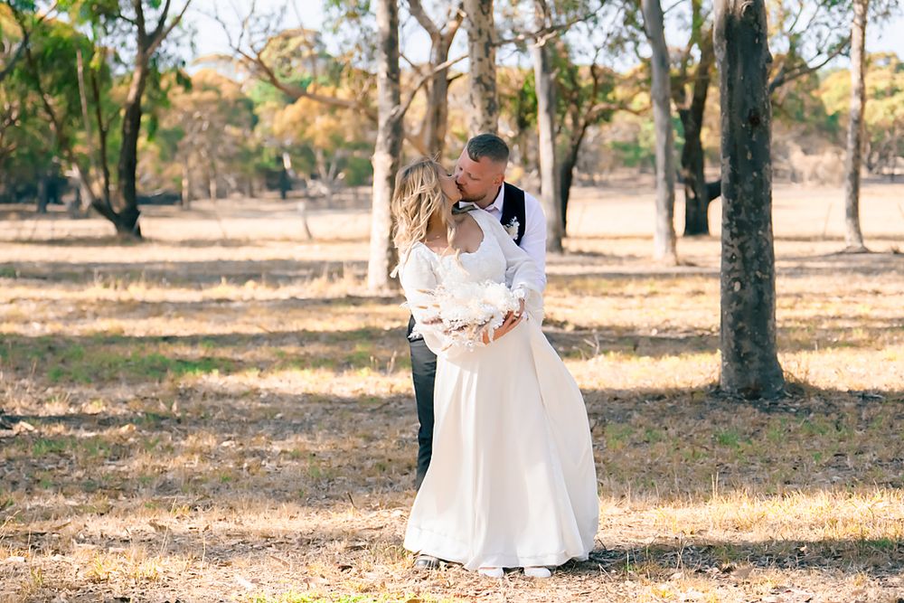 A person in a white dress walks through a sunlit wooded area during autumn creating a dreamy outdoor scene.