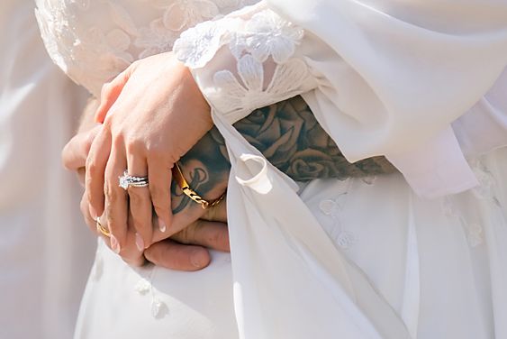 A person wearing a white dress and veil holds a bouquet of pink and white flowers during a wedding ceremony.