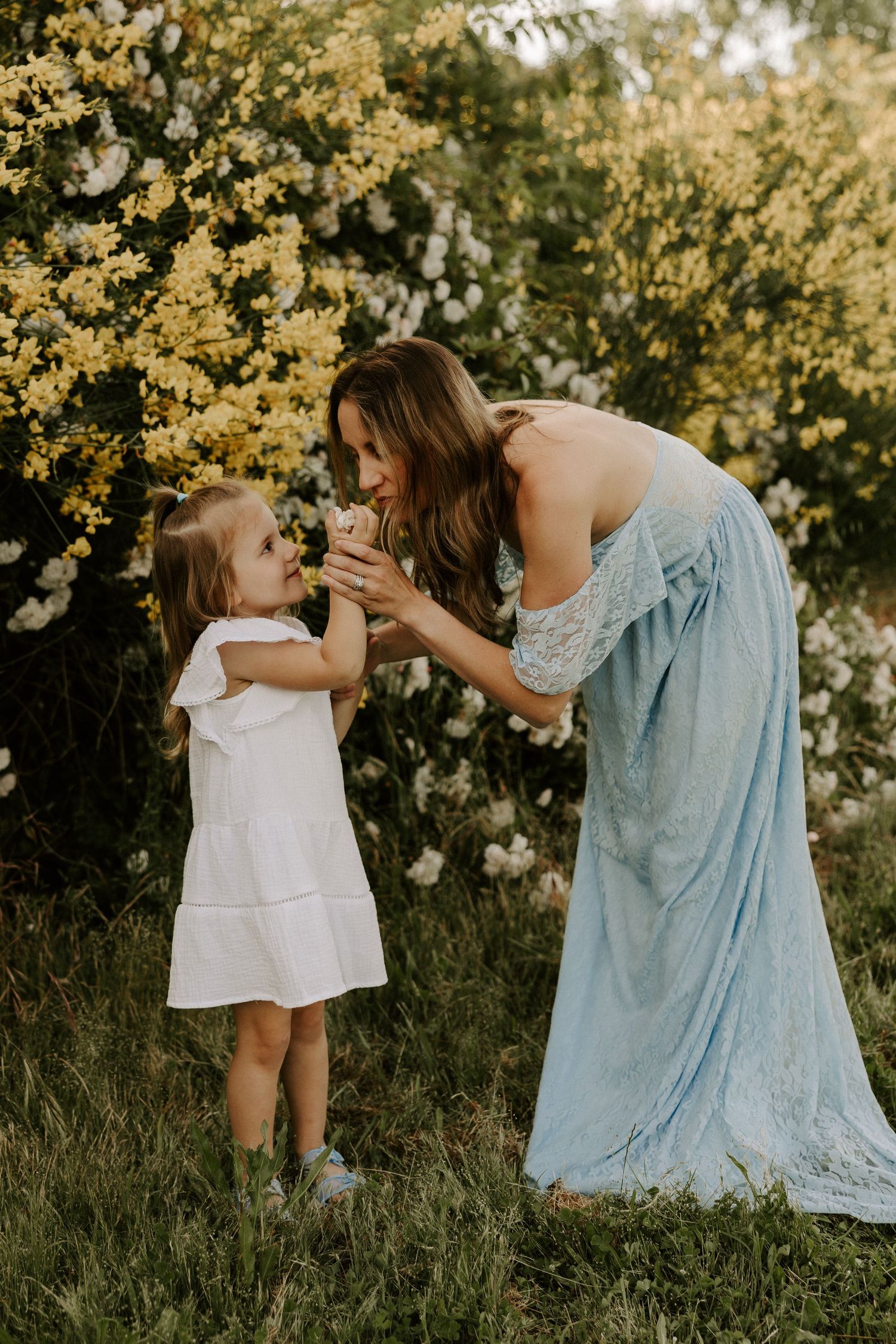 A touching outdoor photoshoot in a garden with white daisies and soft sunlight filtering through the flowers.