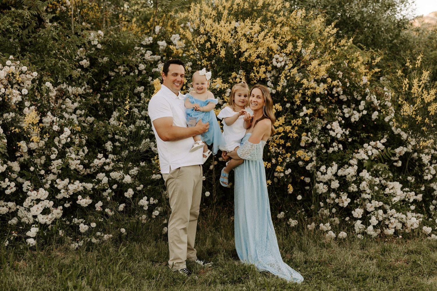 Candid outdoor family photography session among blooming white wildflowers on a sunny afternoon.