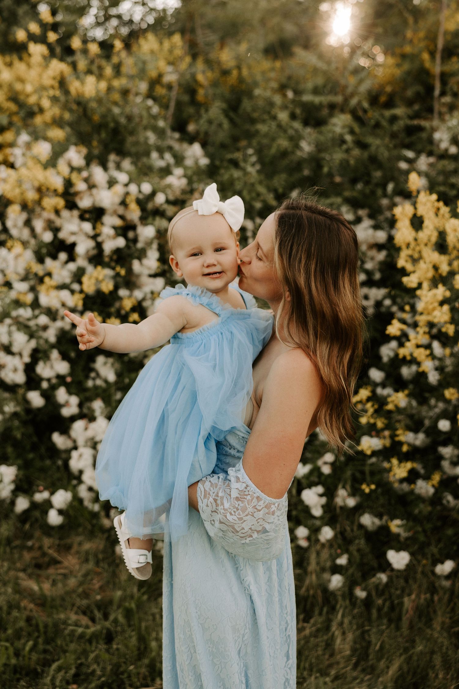 A tender family moment captured against a backdrop of yellow and white blooming flowers.