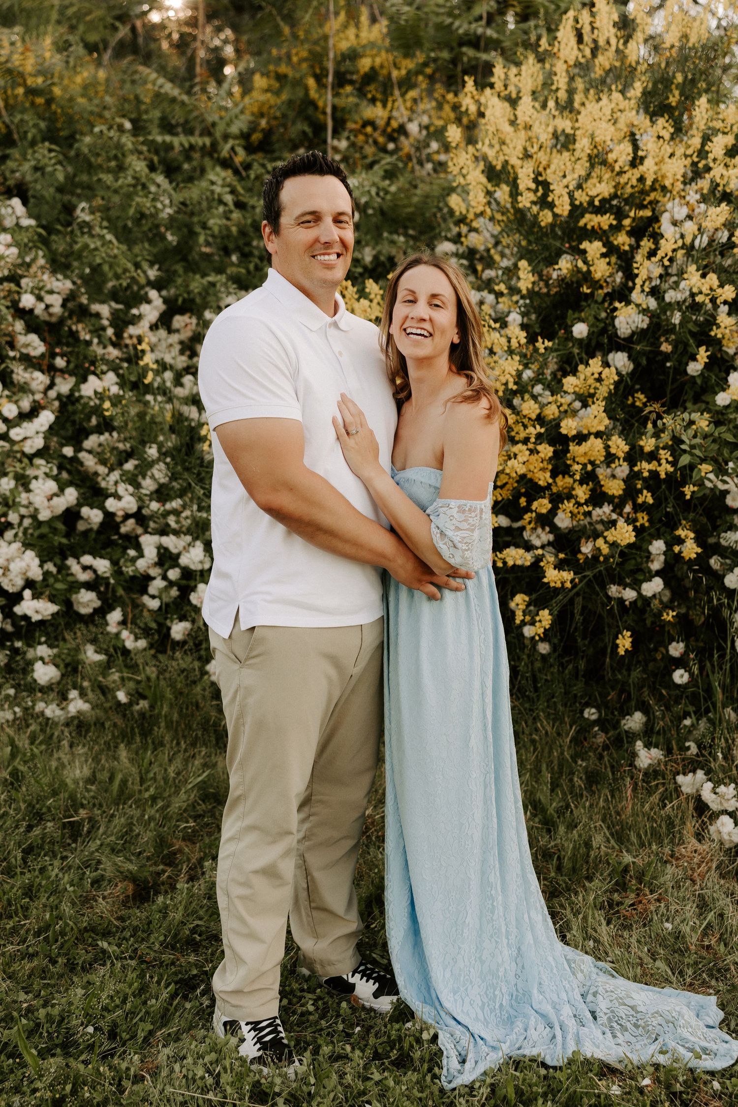 A couple shares joyful moments together in a field of blooming yellow and white flowers.