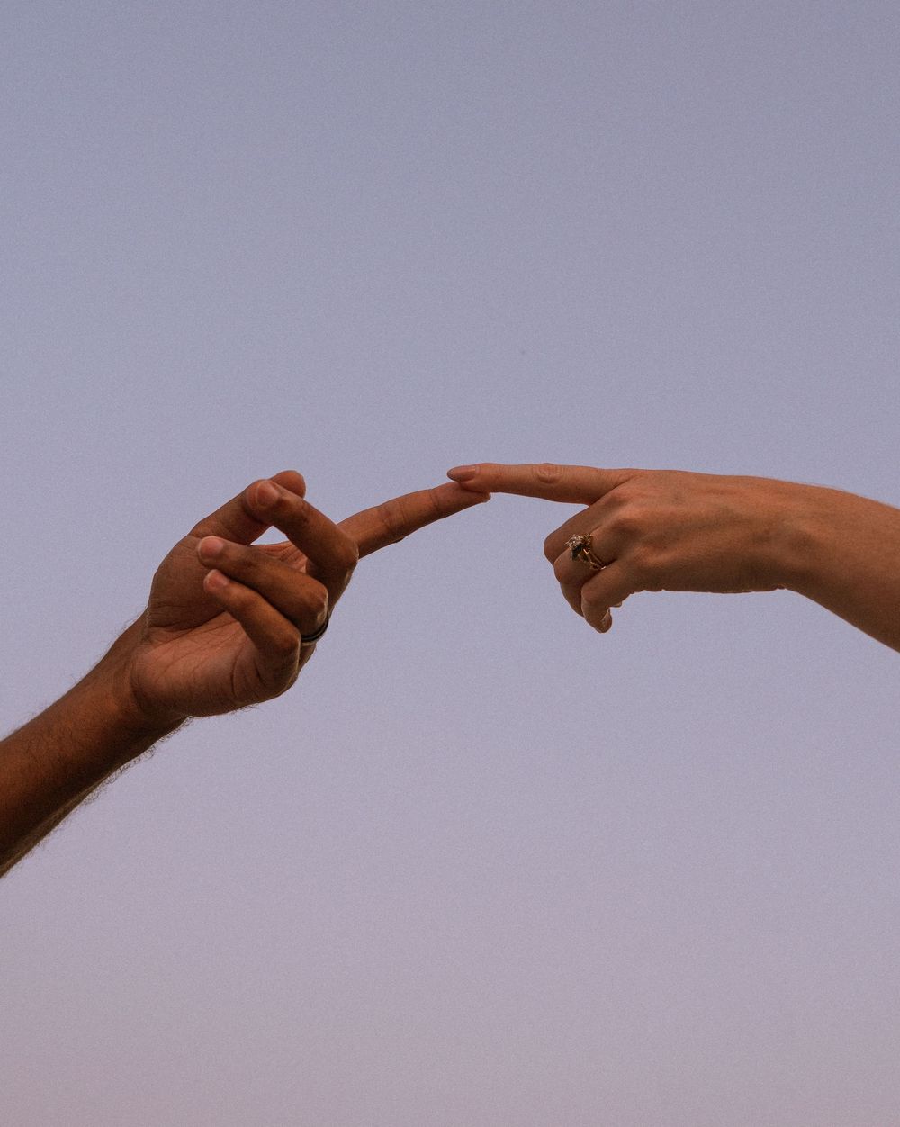 A sequence of hands pointing fingers at each other against a purple sky background in a connected chain formation.