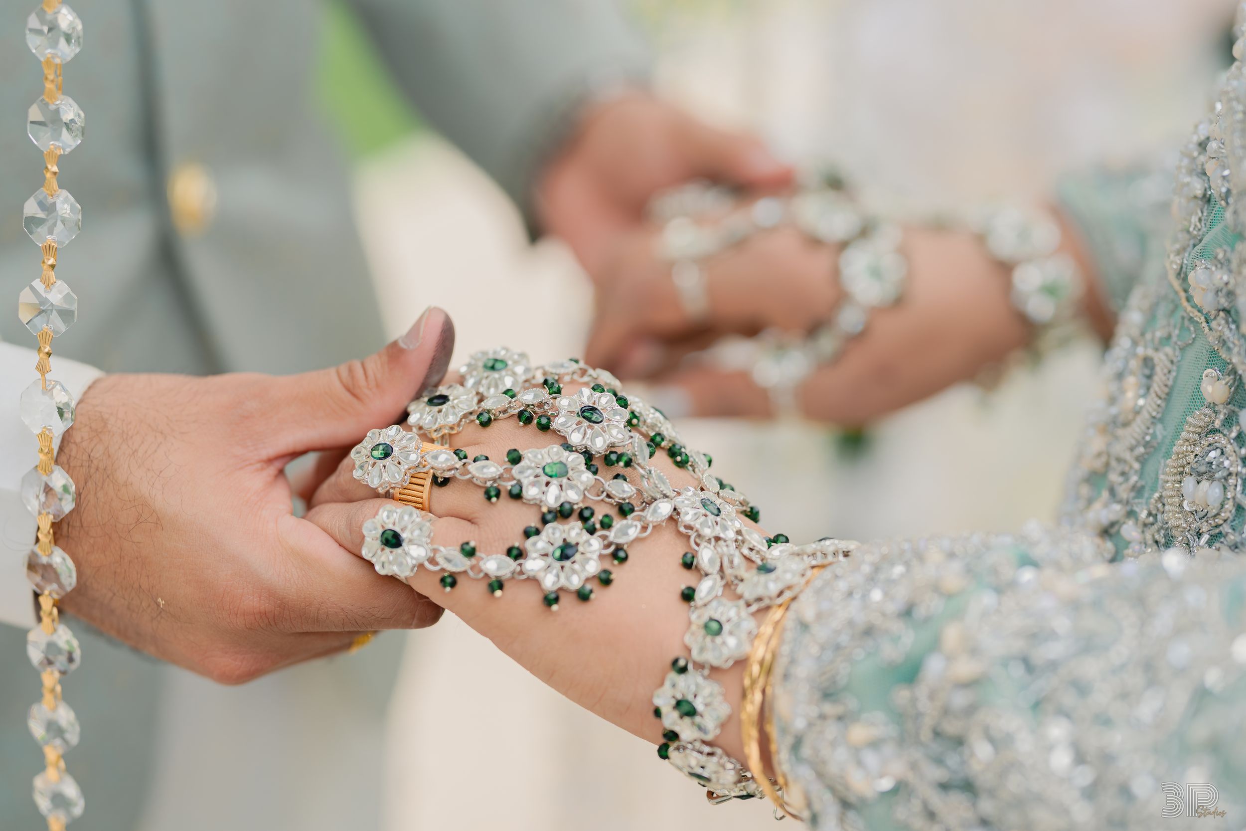 Crystal beaded decorative elements being held up close, showing intricate sparkly details in a wedding setting.