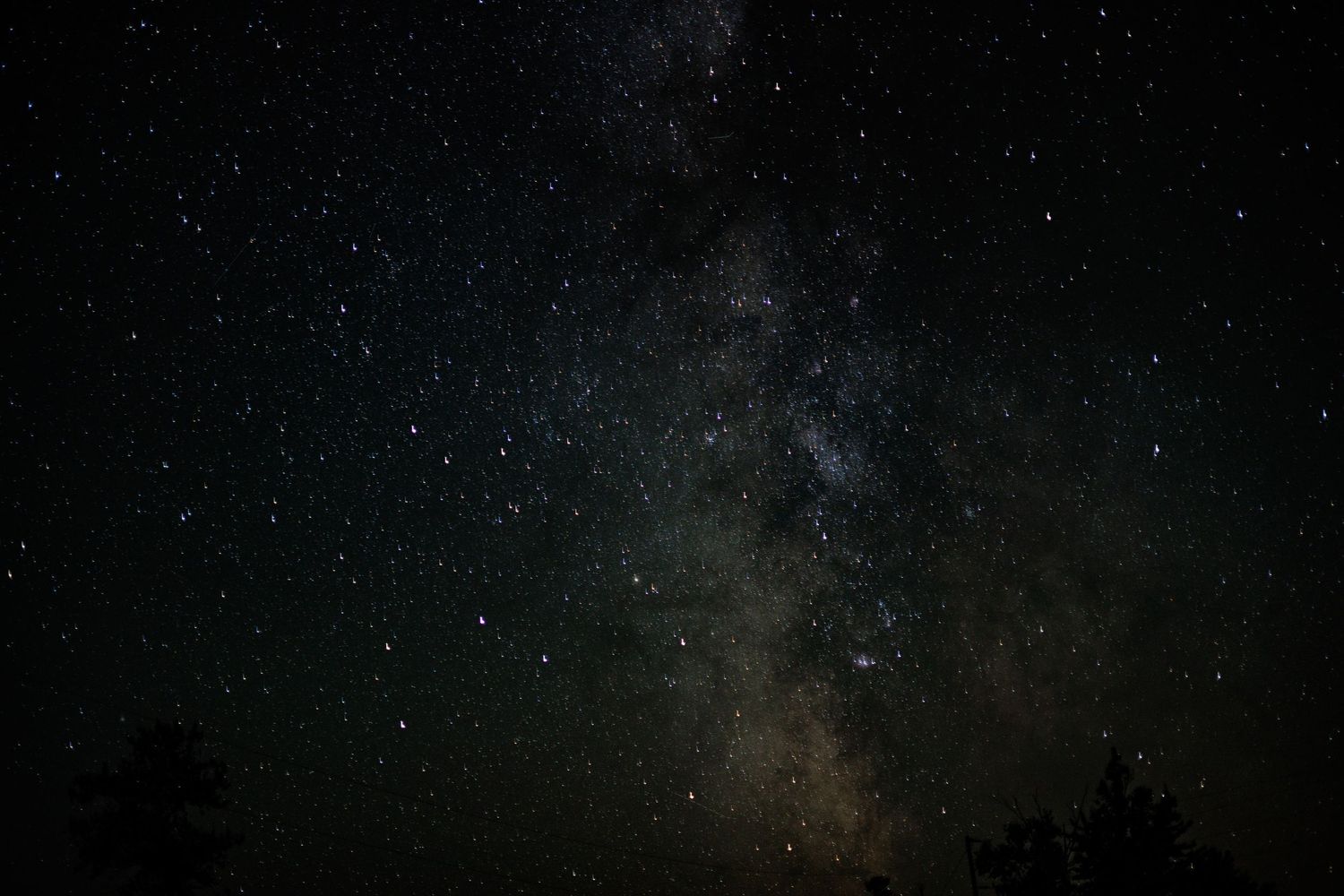 A dark night sky filled with twinkling stars and the Milky Way galaxy stretching across the horizon at Whitefish Point, Michigan